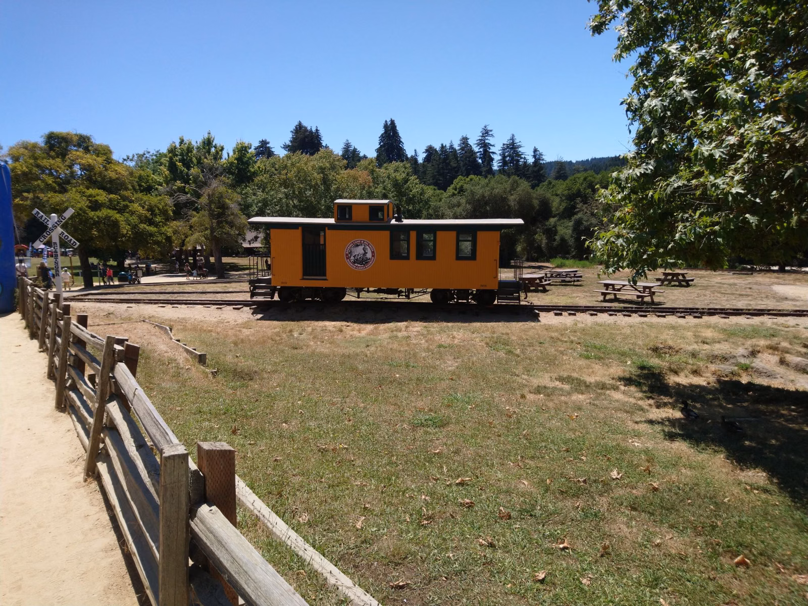 A yellow caboose on display beside the tracks at Roaring Camp in Felton